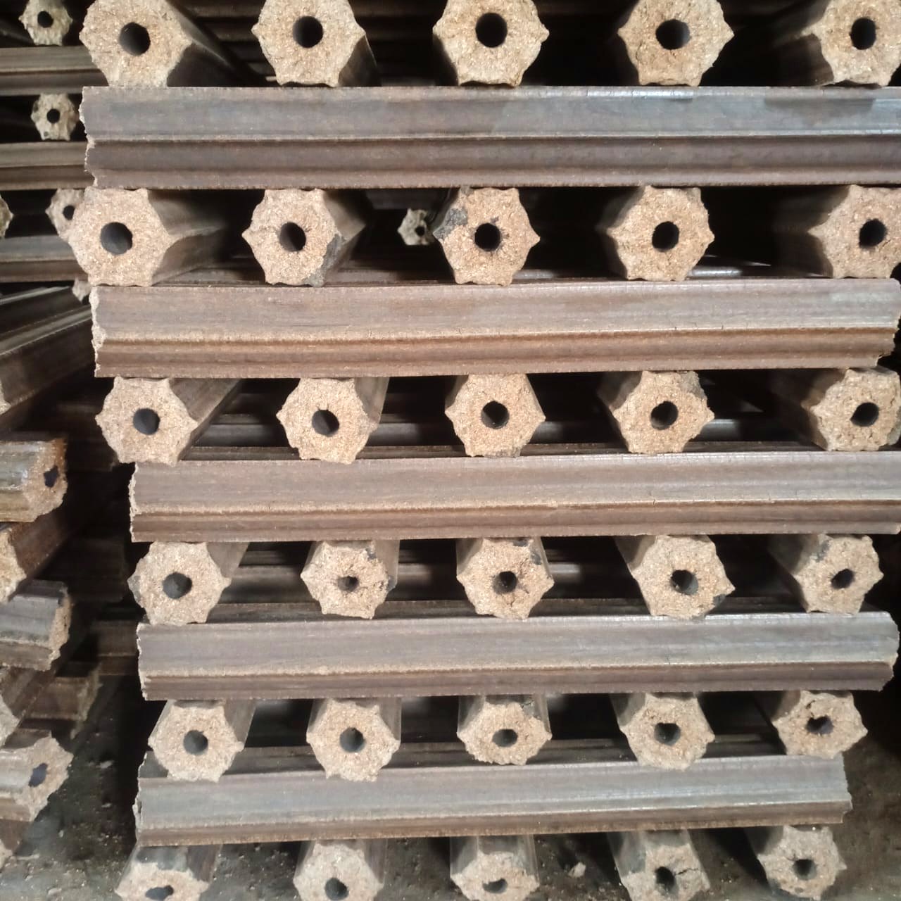 Close-up of hexagonal biomass briquettes with a centre airflow hole